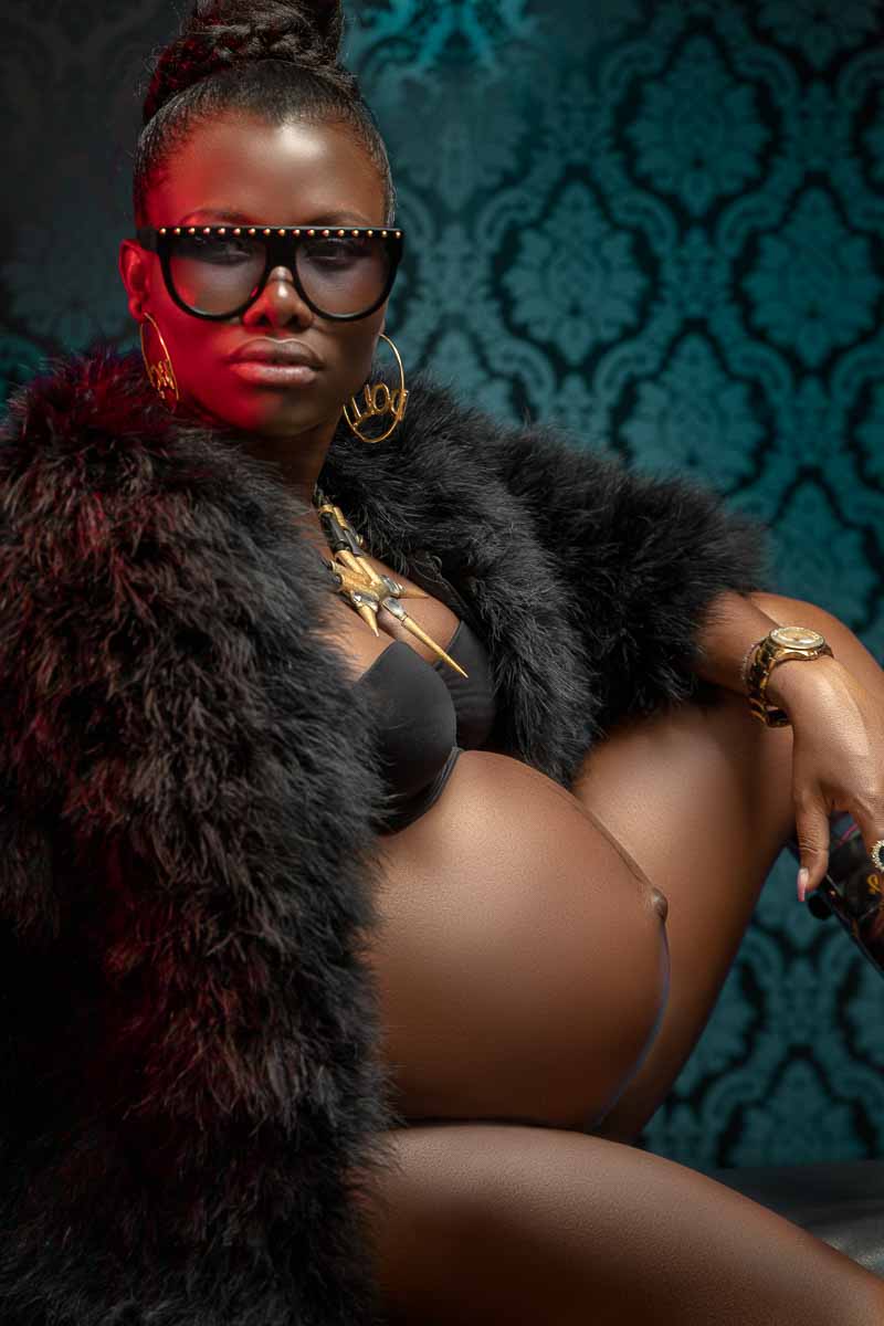 Fotoshooting einer schwangeren dunkelhäutigen Frau, die im Gangster Ghetto-Style in die Kamera schaut