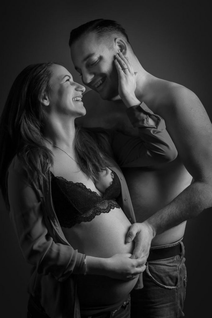 Schwangere Frau mit dickem Babybauch streichelt liebevoll die Wange ihres Mannes