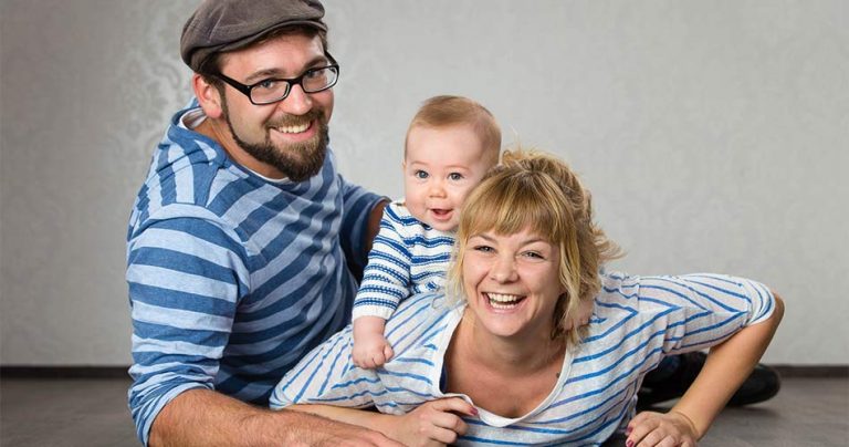 Familie mit blau gestreiften Shirts liegt lachend auf dem Boden