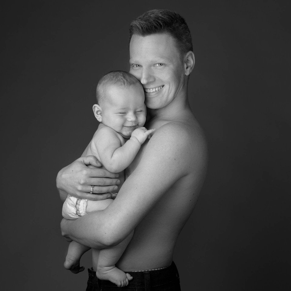 Schwarz-Weiss Foto eines lächelnden Vater, der sein grinsenden Baby umarmt