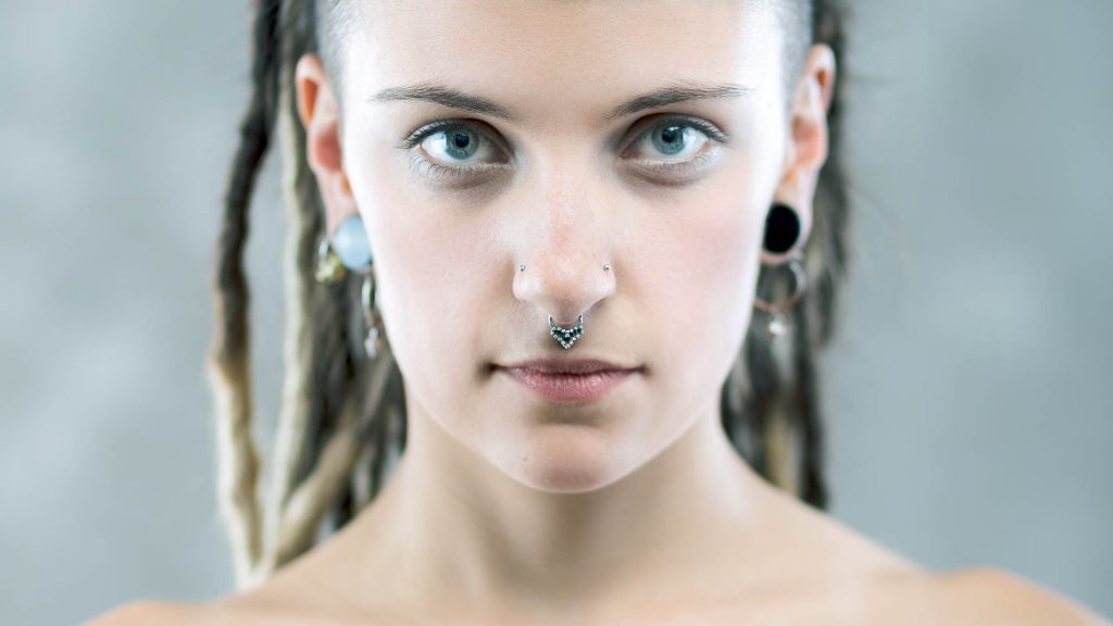 Portraitfoto einer Frau mit Dreadlocks und einem Nasenpiercing